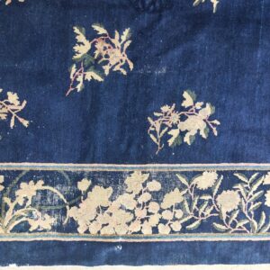 Navy blue rug detail featuring pink and ivory floral patterns and a wide ornamental border band.