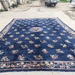 Large navy blue rug with a floral medallion, scattered light floral sprays, and a wide decorative border.