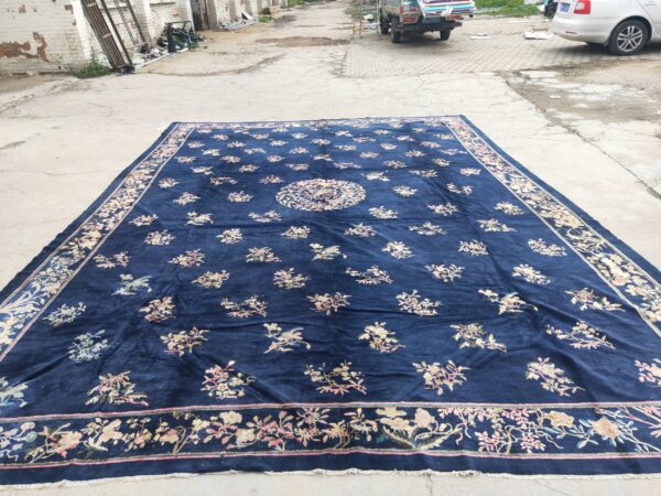 Large navy blue rug with a floral medallion, scattered light floral sprays, and a wide decorative border.