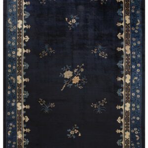 A dark blue rug with contrasting tan and blue stylized floral elements and a wide ornate border.