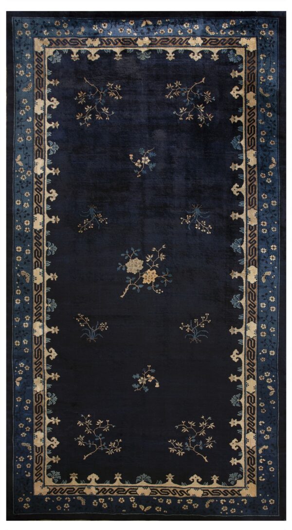 A dark blue rug with contrasting tan and blue stylized floral elements and a wide ornate border.