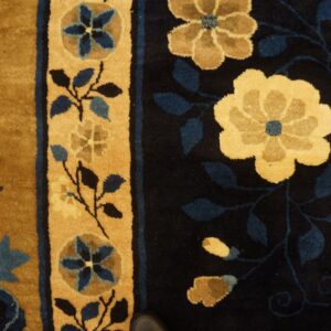 Golden floral motifs and blue leaves on a dark blue field next to a golden striped border.