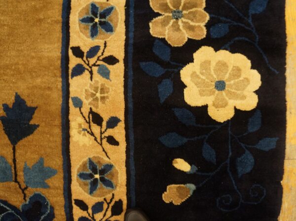 Golden floral motifs and blue leaves on a dark blue field next to a golden striped border.