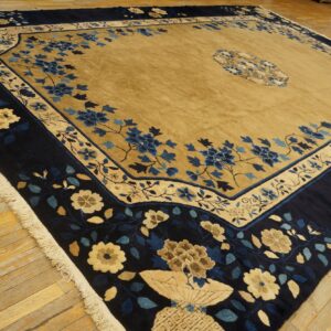 A blue and gold high-pile rug with detailed floral patterns rests on distressed wooden floorboards.