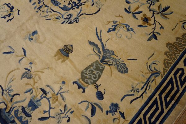 Beige rug with intricate blue and gold chinoiserie patterns and a dark blue geometric key border.