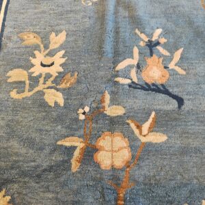 Distressed medium-pile rug featuring a dusty blue field with scattered tan and terracotta floral motifs.