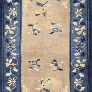 Runner rug with a tan field and detailed blue border showing scattered floral sprigs in blue, cream, and gold.