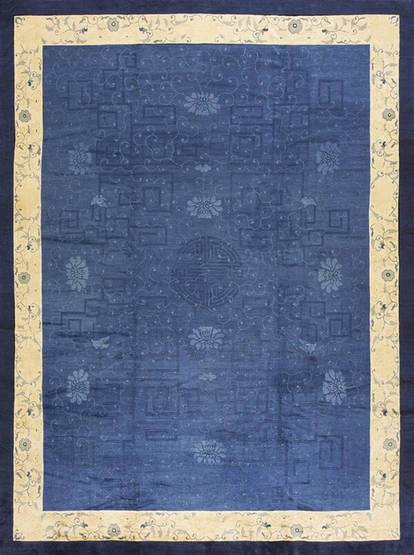 Blue low pile rug with tonal floral and maze patterns, framed by a wide beige and navy blue border.