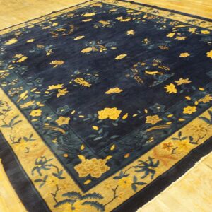 Dark blue rug with contrasting yellow and teal floral patterns on glossy golden wood flooring.