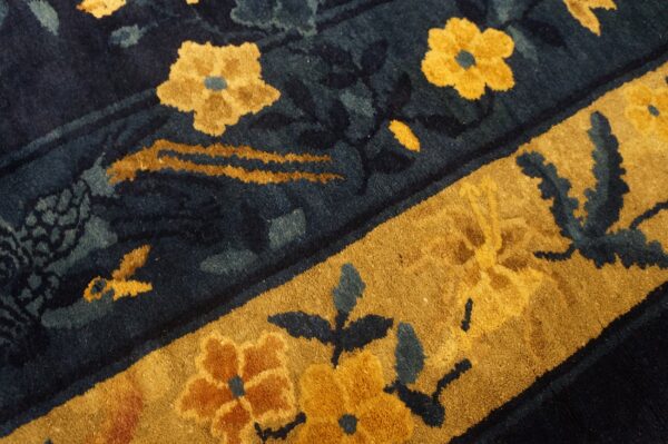 A high-pile rug features dark blue and gold floral patterns with a thick contrasting gold border.