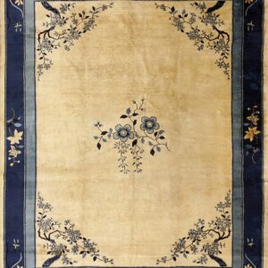 A light gold rug featuring large blue floral corner sprays and wide navy blue striped borders.