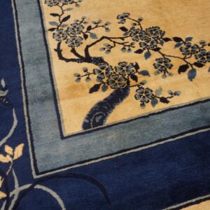 Navy and dusty blue floral vine pattern on a tan field, framed by a multi-banded border.