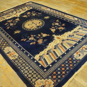 Detailed navy rug featuring a central bird medallion and thick beige borders on light wood flooring.