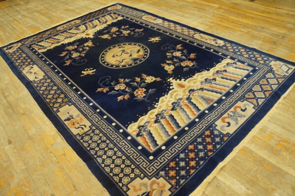 Detailed navy rug featuring a central bird medallion and thick beige borders on light wood flooring.