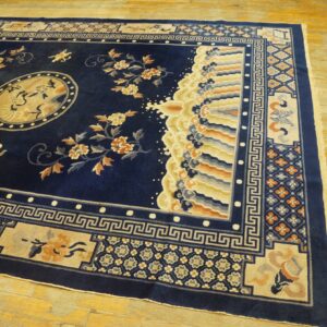 Navy blue rug displays gold floral sprays, a bird medallion, and complex borders on light wooden flooring.