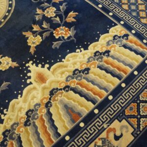 Navy rug with dense floral and wave patterns, surrounded by a border with Greek key and checkered motifs.