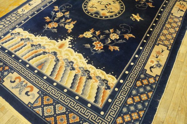 Plush navy blue rug with stylized floral, wave, and geometric patterns rests on light wood flooring.