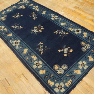 Navy low-pile runner with floral designs and a wide teal and yellow border on wood floorboards.