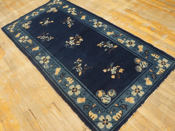 Navy low-pile runner with floral designs and a wide teal and yellow border on wood floorboards.