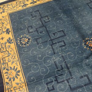Blue field rug with subtle geometric and swirling patterns, framed by a wide gold floral border.