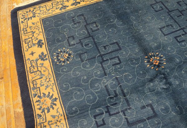 Blue field rug with subtle geometric and swirling patterns, framed by a wide gold floral border.