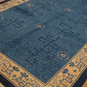 Low pile blue area rug featuring scrollwork, geometric designs, and wide floral borders on wood flooring.
