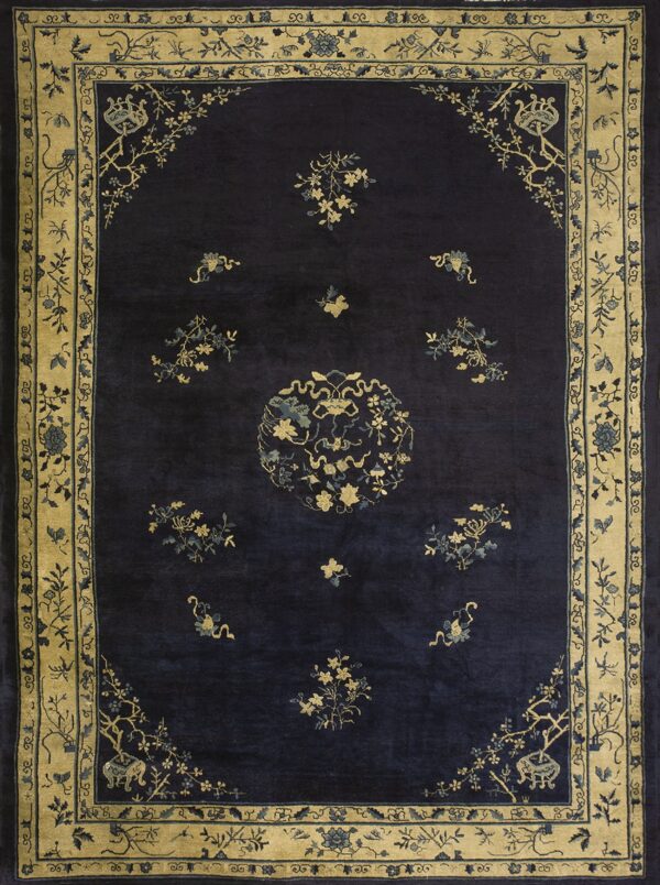 Dark blue rug featuring gold and light blue floral designs, a central medallion, and wide tan borders.
