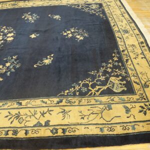 Traditional blue rug with beige borders and intricate floral and vine patterns over light wood floors.