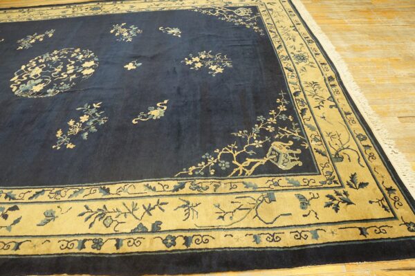 Traditional blue rug with beige borders and intricate floral and vine patterns over light wood floors.