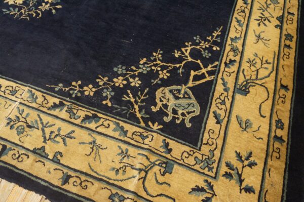 Navy blue rug corner featuring a wide mustard yellow border with teal and gold botanical motifs.