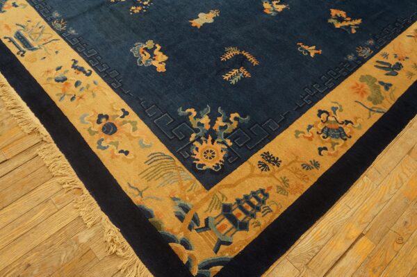 Navy rug with a wide gold border and stylized patterns rests on light wood plank flooring.