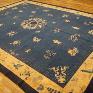 Dark blue rug with a central medallion and scattered gold motifs sits on light hardwood flooring.