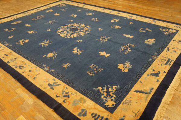 Dark blue rug with a central medallion and scattered gold motifs sits on light hardwood flooring.