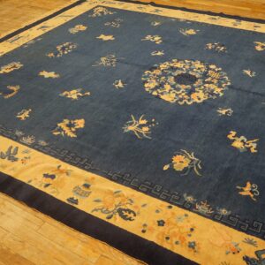 Rectangular dark blue rug featuring a gold border and scattered floral symbols on wood plank flooring.