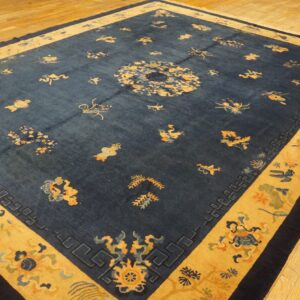Dark blue rug featuring scattered yellow and blue motifs, wide golden borders, and an angled view on wood flooring.