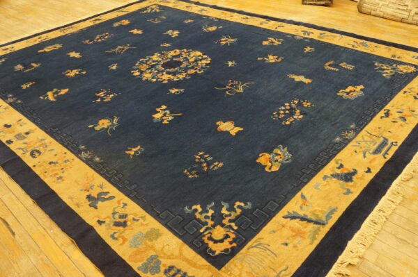 Dark blue rug with scattered gold and blue motifs, wide patterned gold border, on wood flooring.