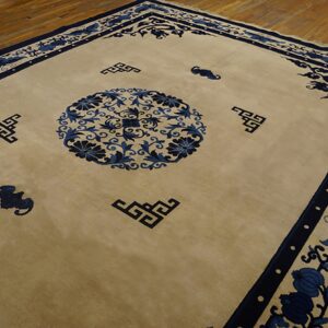 Beige rug with a central blue floral medallion and dark blue geometric borders on hardwood flooring.