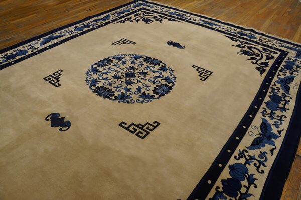 Beige rug with a central blue floral medallion and dark blue geometric borders on hardwood flooring.