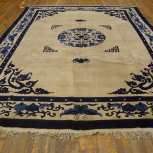Beige rug featuring deep blue border, central medallion, and stylized floral motifs on wood planks.