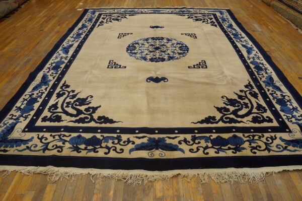 Beige rug featuring deep blue border, central medallion, and stylized floral motifs on wood planks.