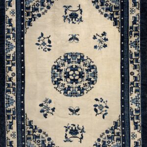 Off-white rug featuring navy and light blue geometric borders and stylized floral patterns.