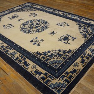 Cream and blue rug featuring a central medallion and detailed geometric and floral borders on wood floor.