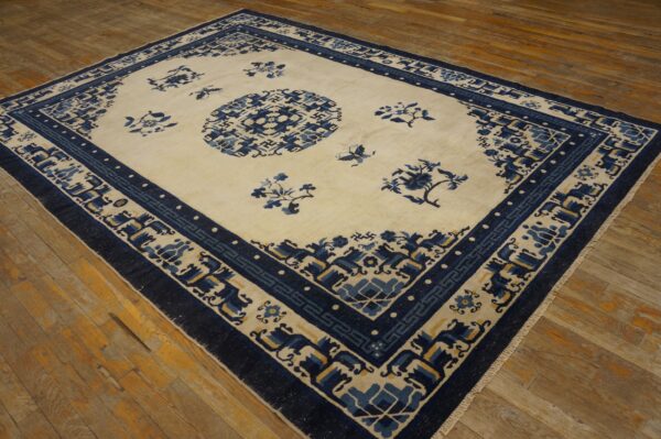 Cream and blue rug featuring a central medallion and detailed geometric and floral borders on wood floor.