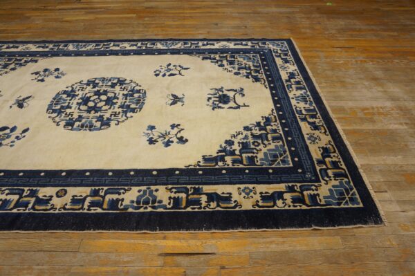 Cream rug with navy blue and yellow geometric patterns rests on rustic wooden flooring.