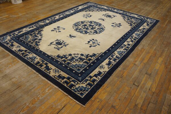 Blue and cream patterned rug with a central medallion lies on distressed wooden plank flooring.