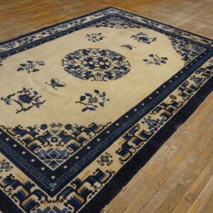 Light blue and cream rug featuring floral patterns and geometric borders on worn hardwood flooring.