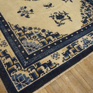 Cream and blue rug featuring scattered flowers, butterflies, and a detailed border on aged wood planks.