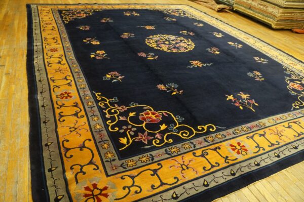 Deep blue rug with bright yellow borders and colorful floral motifs lying on light wood planks.