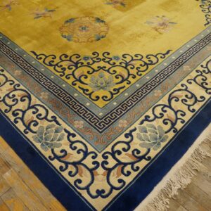 The vibrant gold rug has intricate navy and light blue borders featuring floral and geometric patterns on hardwood floors.