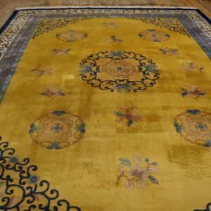 Gold rug with high luster, traditional blue floral medallions, intricate borders, and displayed on worn wood planks.